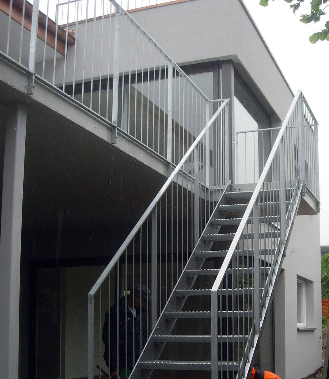 Aussentreppe mit Metallwangen und Gitterroststufen. Geländer mit Sprossen und Rahmen aus Flachstahl. Alle Metallteile feuerverzinkt.