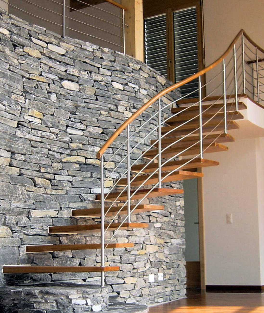 Marches à encorbellement en bois massif avec balustrade rampante en inox et main courante en bois.