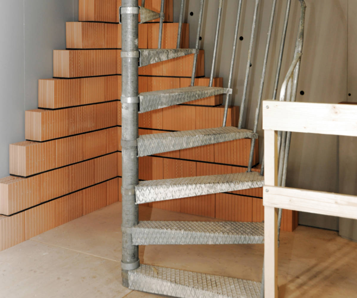 Escalier de chantier en colimaçon métallique avec balustrade rampante.