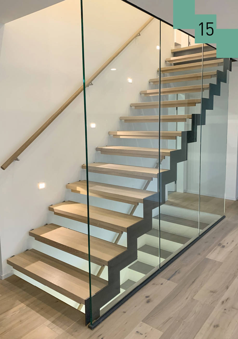 Massivholzstufen in Wand montiert, aussen in abgetreppte Metallwange. Die Treppe wird mit raumhohem Glas von dem Raum getrennt. 