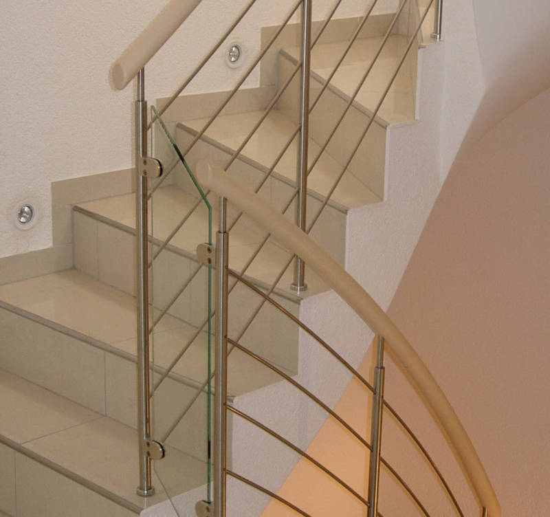Balustrade rampante type Reling en inox sur escalier béton, avec main courante en bois. Remplissage entre les volées en verre.