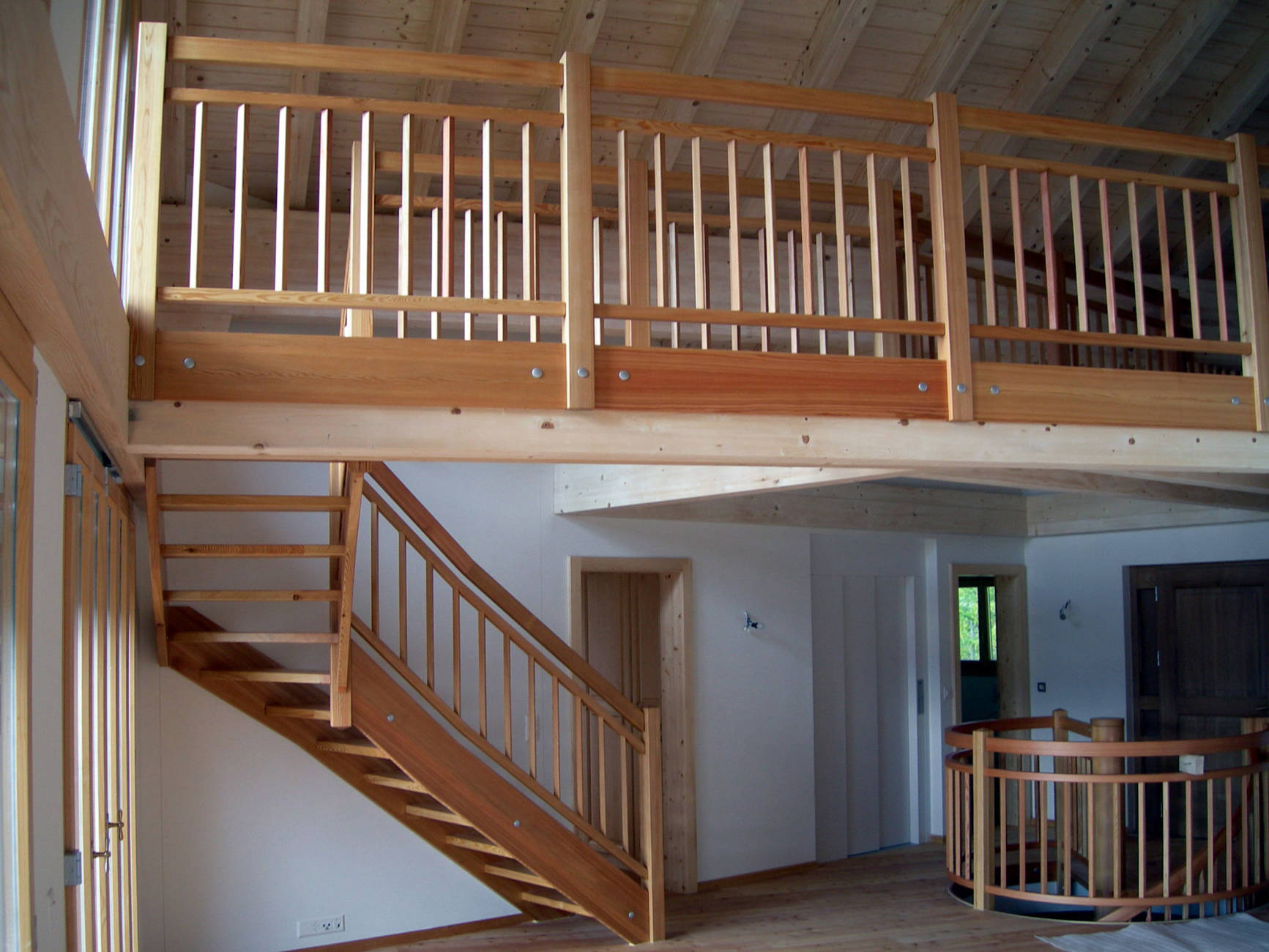 Escalier à limons et rampes en bois. Les balustres verticaux sont fixés sur une lisse basse et haute entre les limons et la main courante.