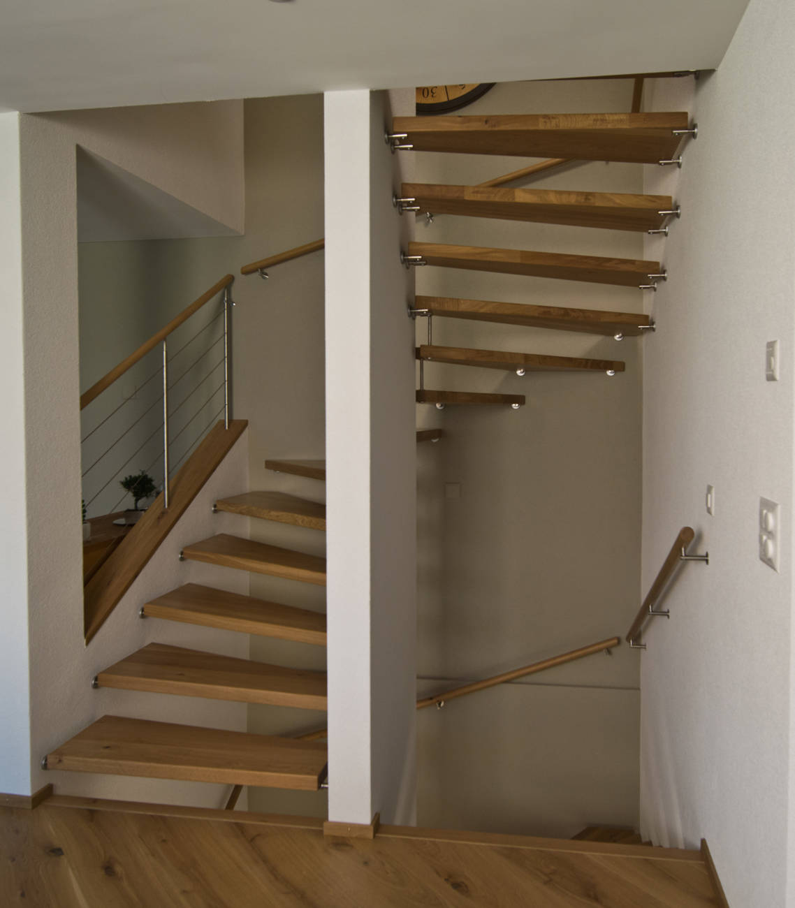 Eichestufen zwischen Wände mit Seitengeländer und Holzhandläufe an Wand.