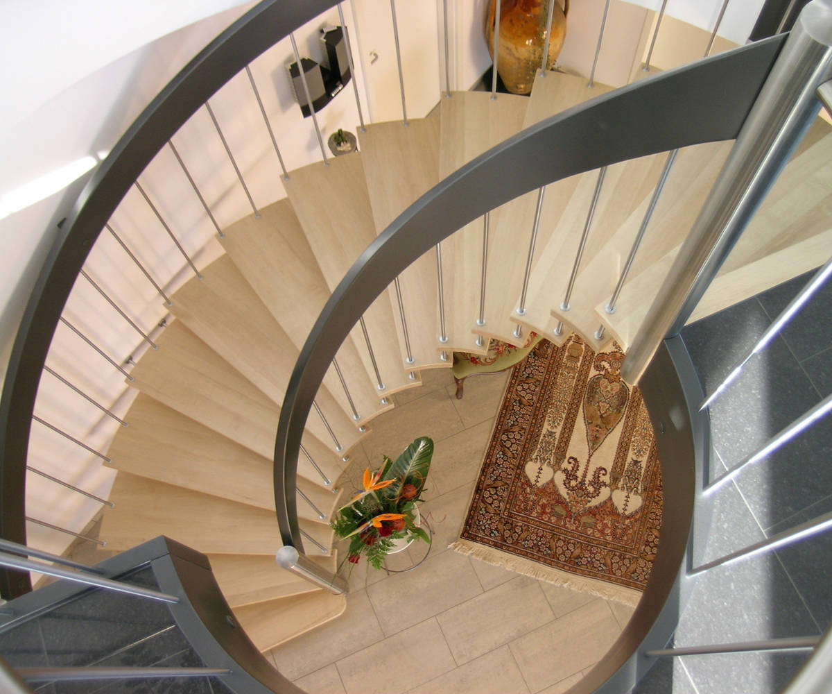Freitragende Bogentreppe mit beidseitigem Sprossengeländer. Stufen in Buche, Handlauf farbig deckend versiegelt, Sprossen und Pfosten in Edelstahl.
