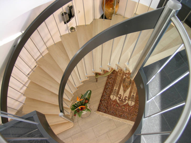 Freitragende Bogentreppe mit beidseitigem Sprossengeländer. Stufen in Buche, Handlauf farbig deckend versiegelt, Sprossen und Pfosten in Edelstahl.