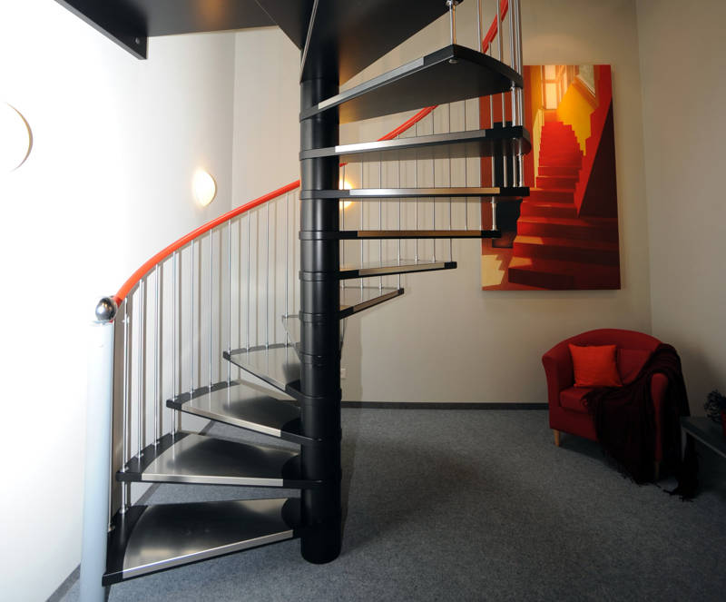 Spindeltreppe in Massivholz, Stufen und Säule schwarz und Handlauf orange deckend versiegelt. Stufenauflagen, Pfosten und Geländersprossen in Edelstahl.
