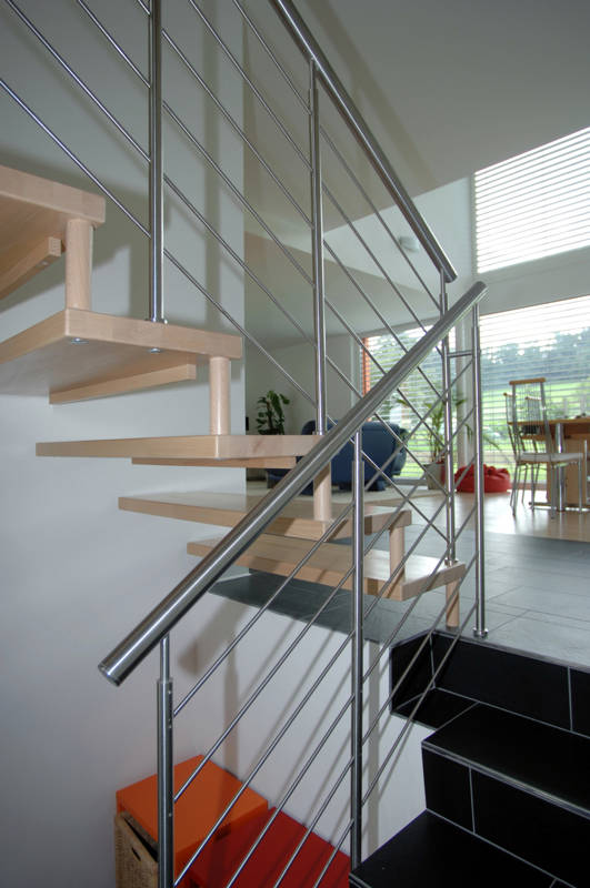 Treppengeländer in Edelstahl mit CNS-Handlauf an Betontreppe befestigt. Ins nächste Stockwerk führt eine Freitragende Treppe.