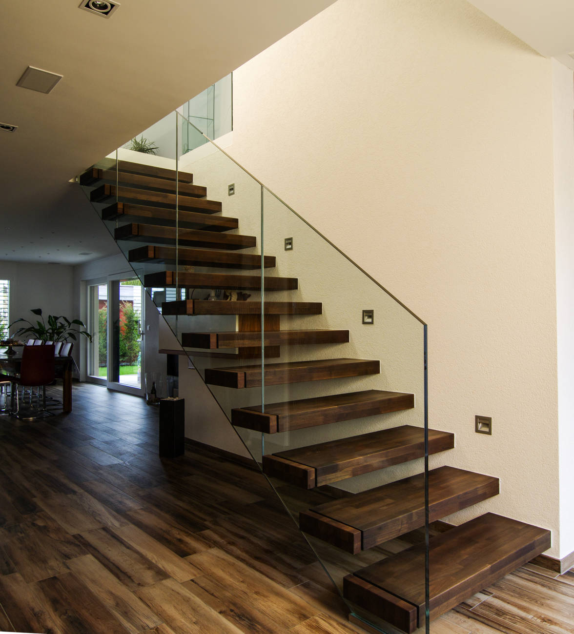 Marches à encorbellement en acacia abouté collé, huilé foncé. Rampe en verre sécurisé.