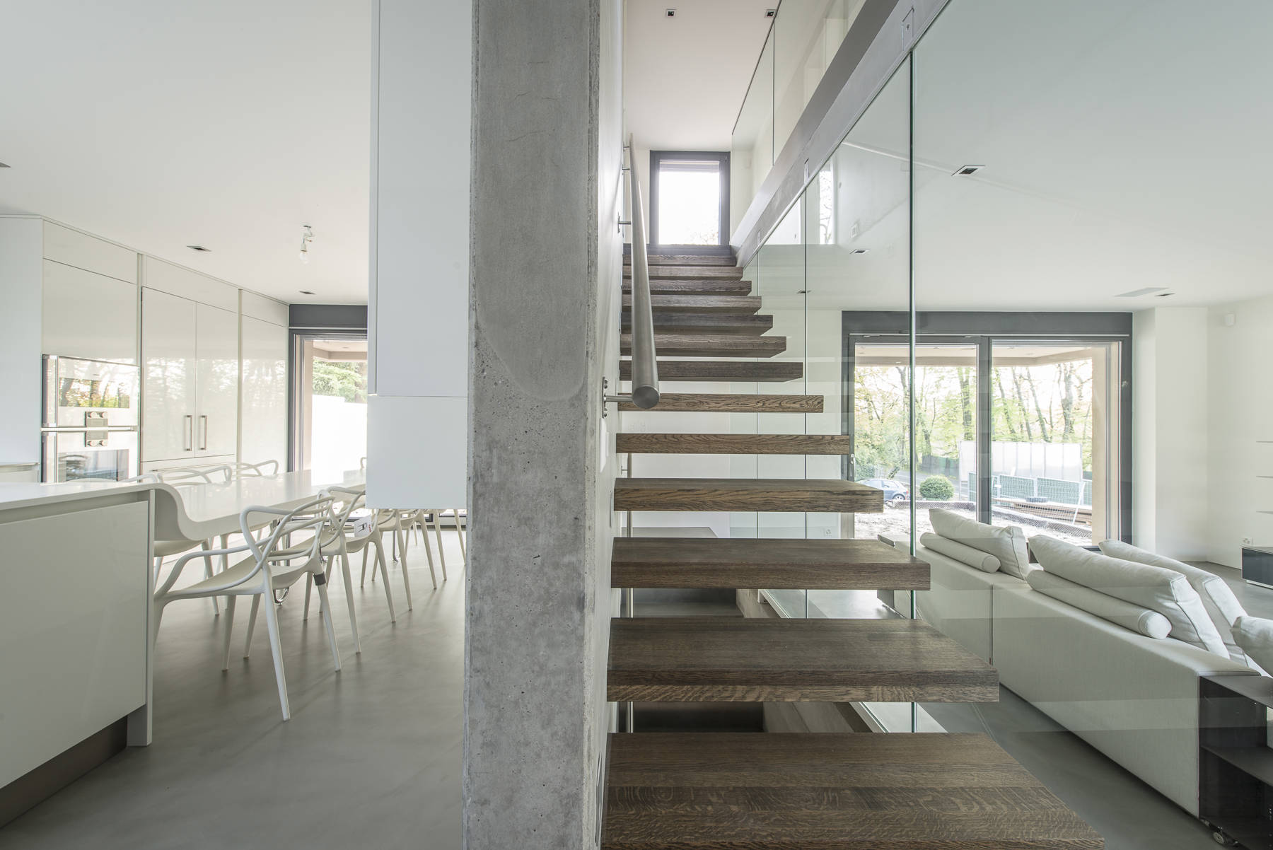 Marches à encorbellement en chêne huilé noir. Paroi en verre et côté mur une main-courante en inox.