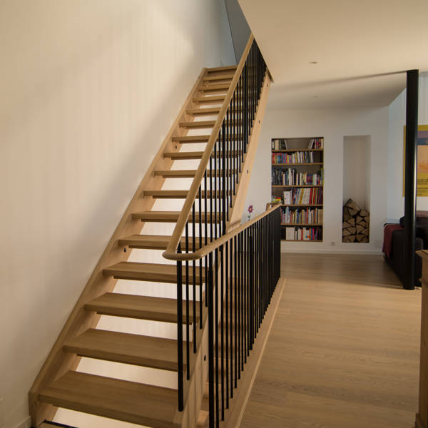 Escalier avec limons, marches et main-courante en chêne. Barreaux en métal couleur RAL 9011 noir graphite, mat.