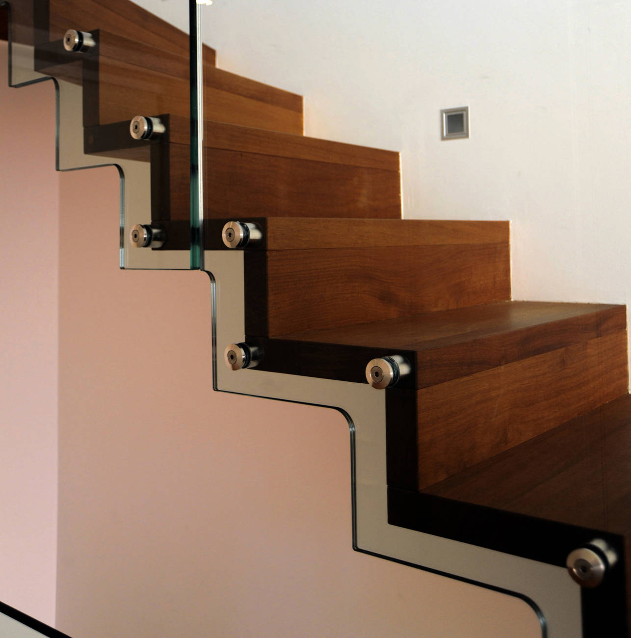Faltwerktreppe aus Massivholz, mit der Wand verschraubt. Glasbrüstung seitlich mit Swisspoint-Haltern an Treppe befestigt.