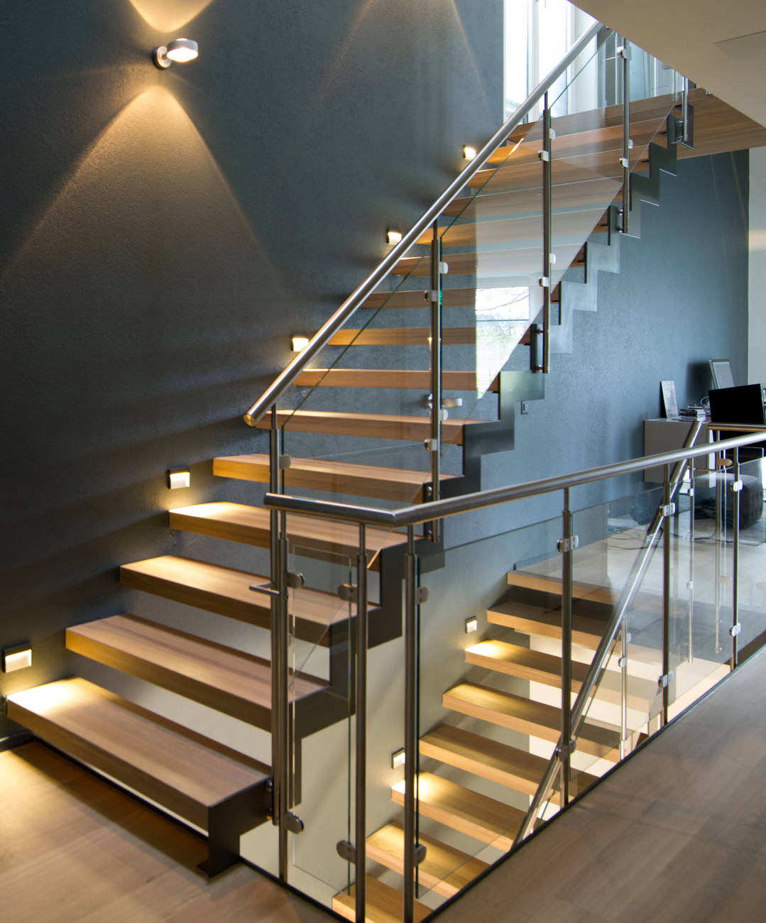 Stufen in Eiche weiss geölt, innen mit abgetreppter Metallwange und aussen direkt in Wand befestigt. Geländer mit Edelstahlpfosten, Verbundsicherheitsglas und CNS-Handlauf.