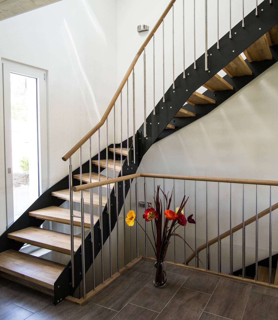 Loft-Treppe, Stufen in Eiche längsgezinkt weiss geölt zwischen Vollkernplatten geschraubt. Geländer mit vertikalen Edelstahlsprossen und rundem Holzhandlauf. Kinderschutzleisten in Holz.