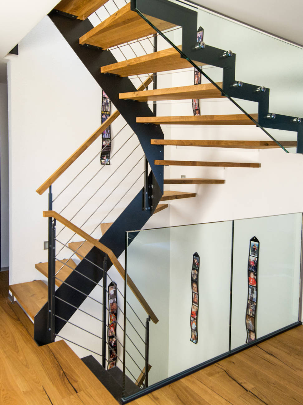 Metallwangentreppe, Stufen in Eiche, innen mit Metallwange, aussen direkt in Wand befestigt. Geländer mit quadratischen Pfosten, liegenden Edelstahlgurten und Holzhandlauf. Kinderschutzleisten in Plexiglas. Abschlussgeländer aus Verbundsicherheitsglas.