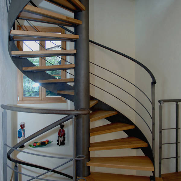 Escalier colimaçon avec marches en chêne, vitrifiées couleur naturelle, fût central, limon et rampe en acier finition thermo-laqué.