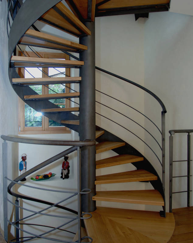 Escalier colimaçon avec marches en chêne, vitrifiées couleur naturelle, fût central, limon et rampe en acier finition thermo-laqué.