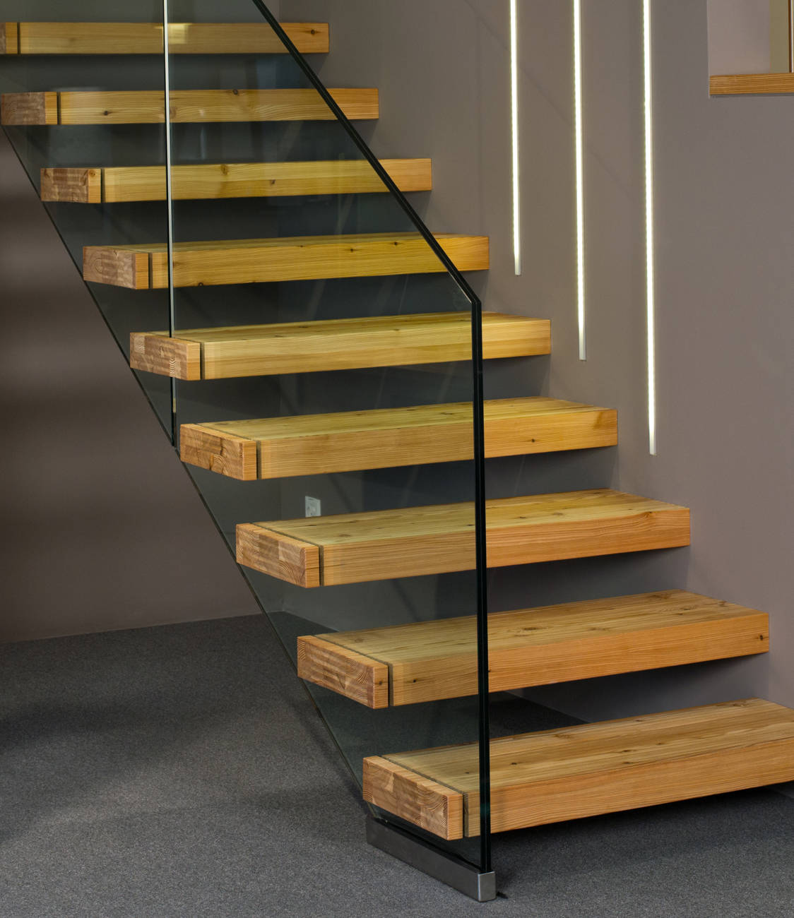 Marches à encorbellement en mélèze avec noeuds, raboté et huilé. Rampe en verre sécurisé.