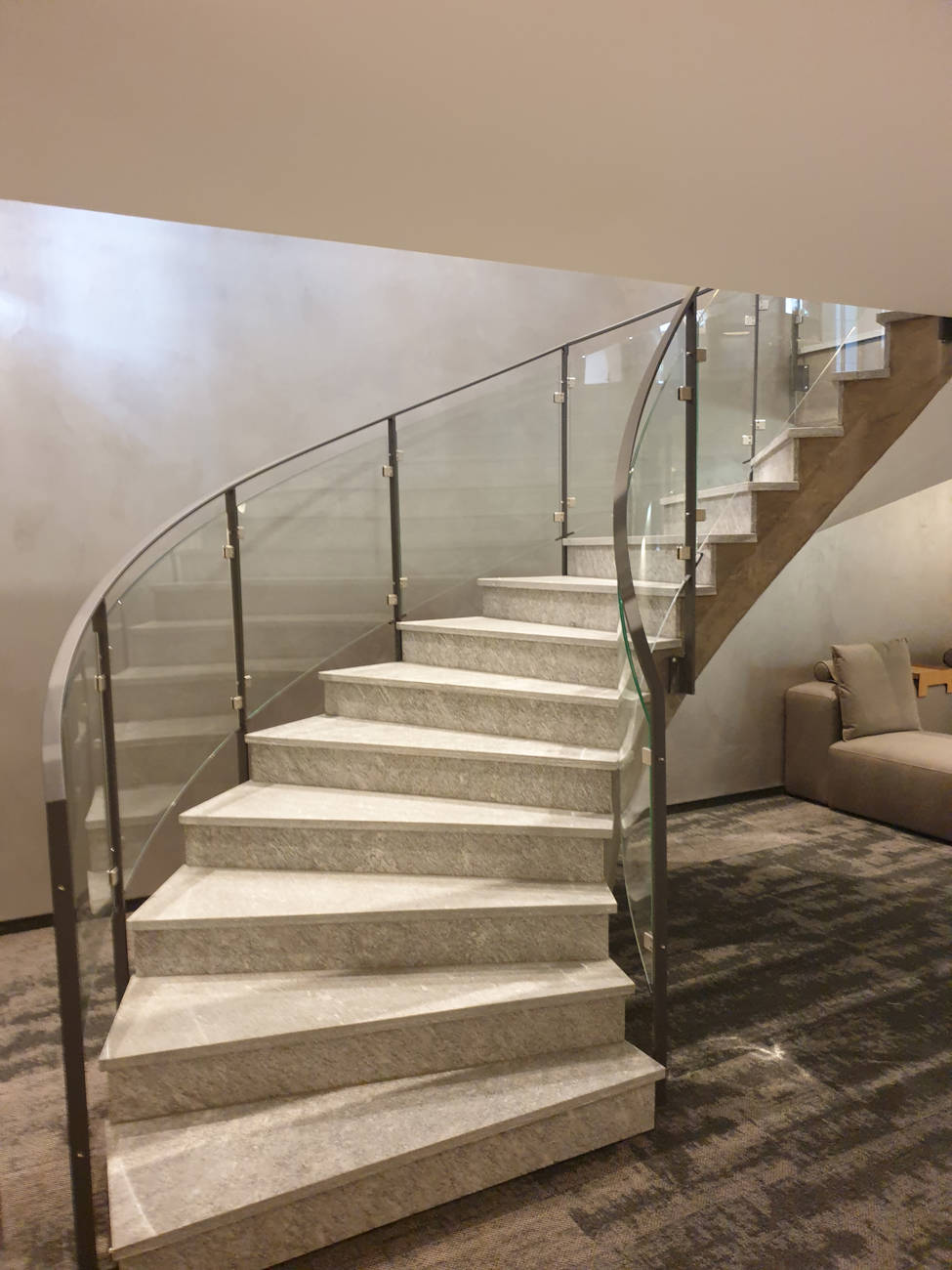 Flachstahlgeländer grau pulverbeschichtet. Glasfüllungen (VSG) mit spez. CNS-Glashaltern zwischen die Pfosten montiert.