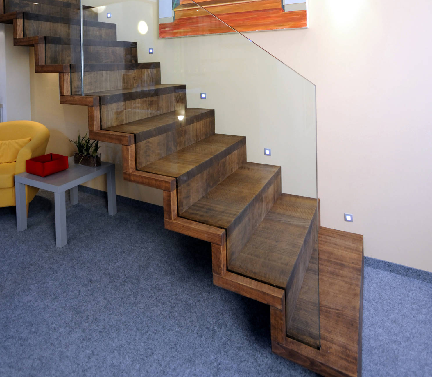 Faltwerktreppe aus Buche dunkel geölt, mit der Wand verschraubt. Glasbrüstung lichtseitig ins Massivholz eingenutet.