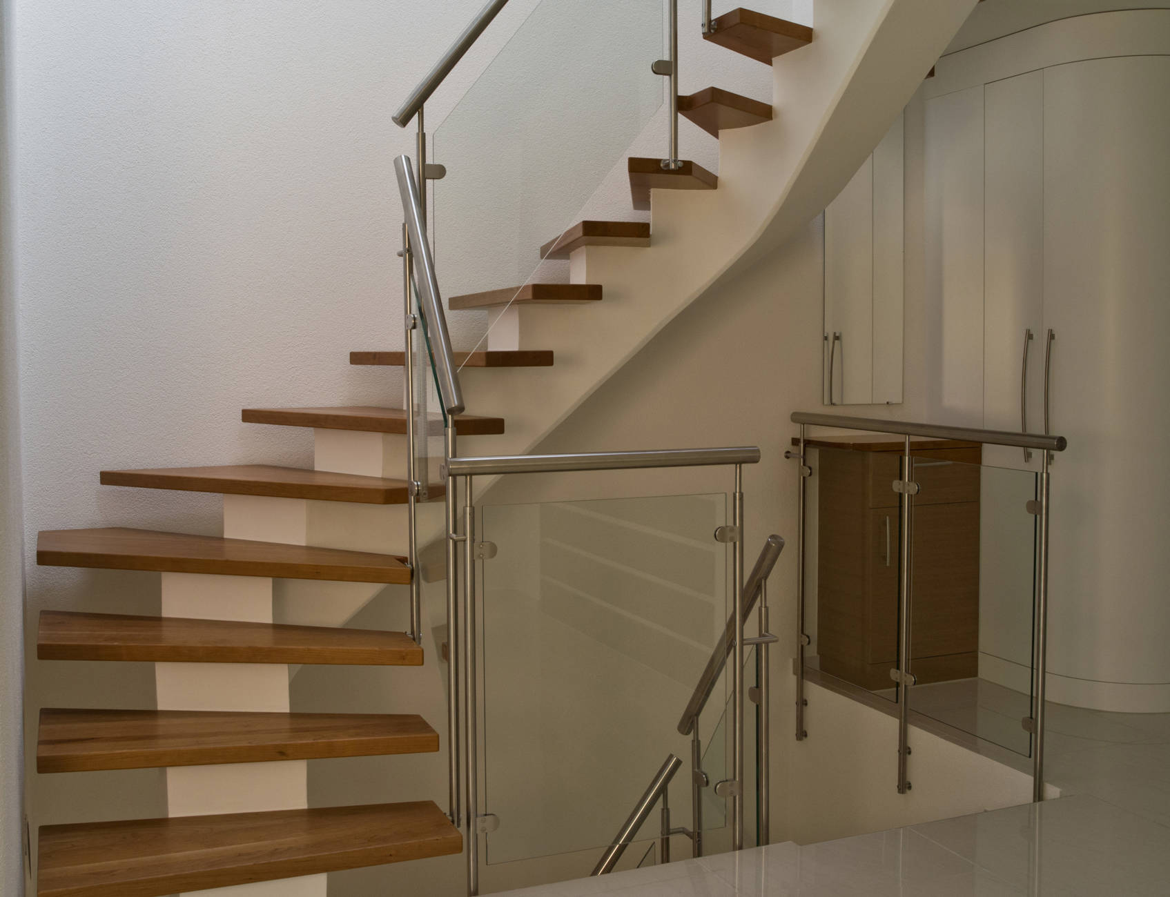 Massivholzstufen auf Betonsattel. Geländer mit Edelstahlpfosten, CNS-Handlauf und Verbundsicherheitsglas.