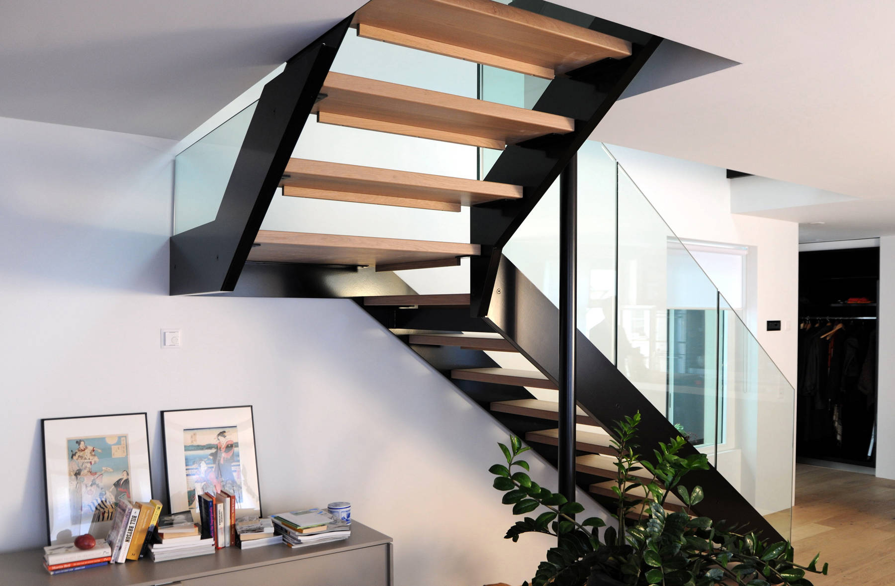 Escalier à limons métalliques et marches en bois massif, rampes avec panneaux en verre. Listes de sécurité en bois.