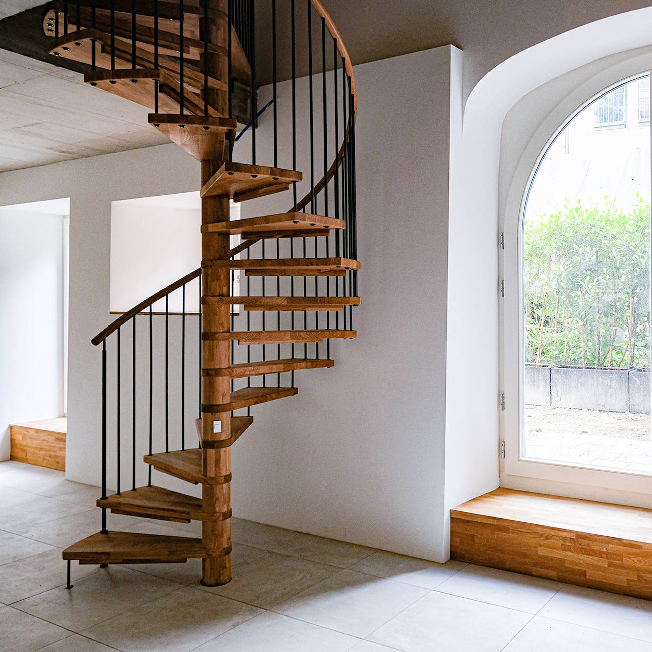 Spindeltreppe in Eiche längsgezinkt, natur geölt. Kinderschutzleisten in Holz. Treppengeländer mit Schwarzstahlsprossen und einem Handlauf in Eiche. 