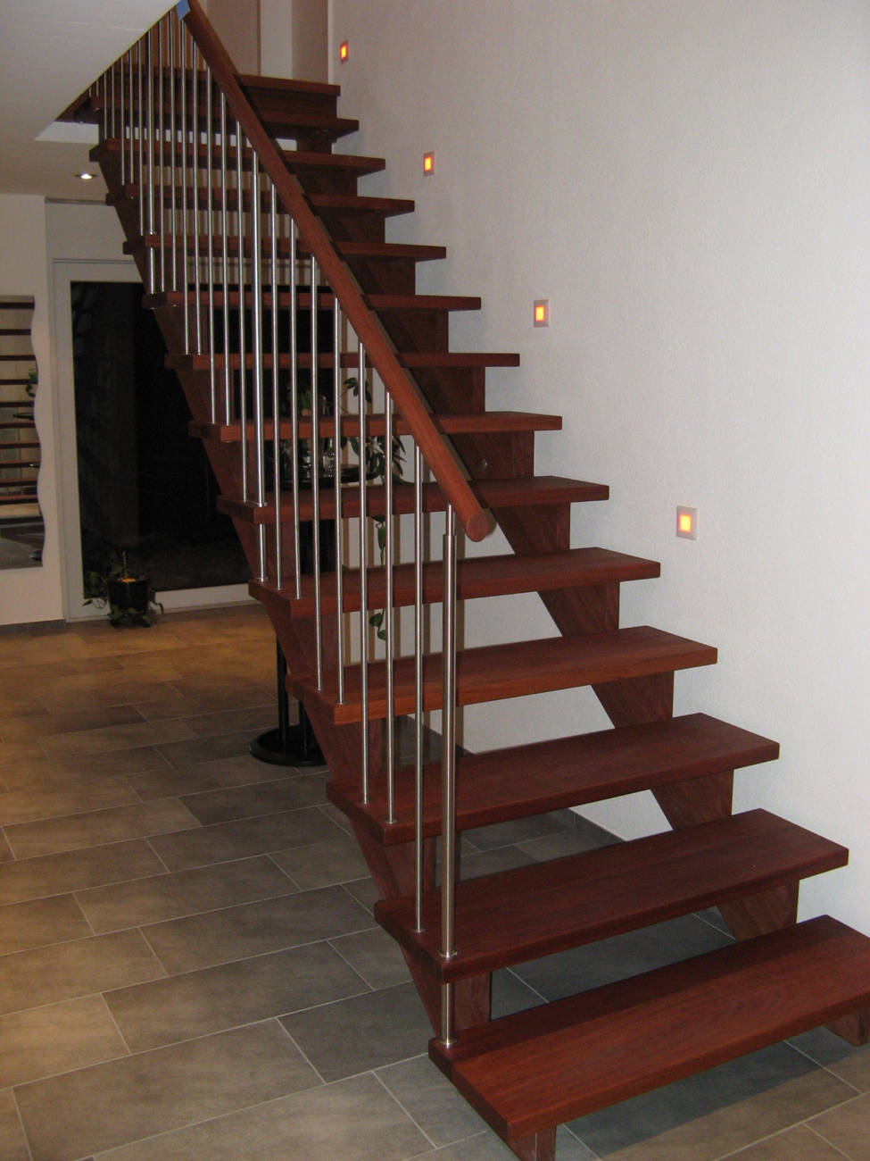 Main courante, marches et limons en "Jatoba" huilé. Les balustres en inox sont fixés dans la main courante ronde Ø 45 mm - en partie haute et dans les marches en partire inférieure.