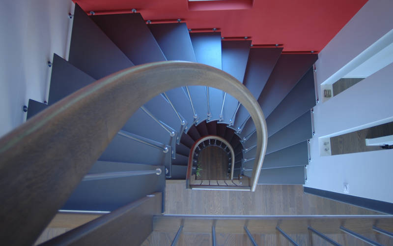 Escalier demi tournant, courbe, et balustres en inox. Marches laquées couleur au rouleau et main courante en bois.