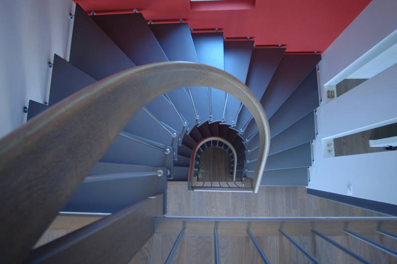 Freitragende halbgewendelte Treppe mit gebogenem Handlauf und Edelstahlsprossen. Stufen farbig deckend versiegelt und Handlauf in Holz.