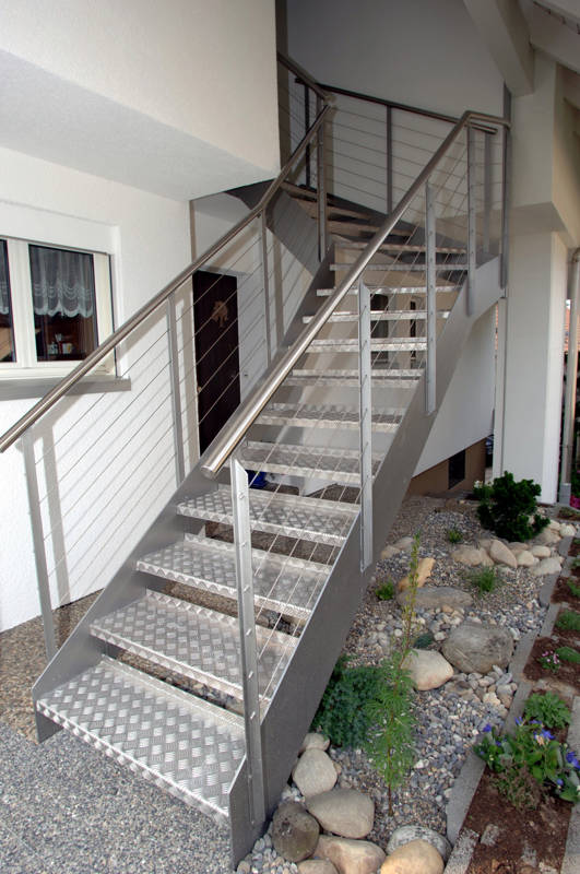 Escalier d'extérieur avec limons métalliques, balustrades montantes des 2 côtés avec poteaux en fer T, main courante et câbles en inox.