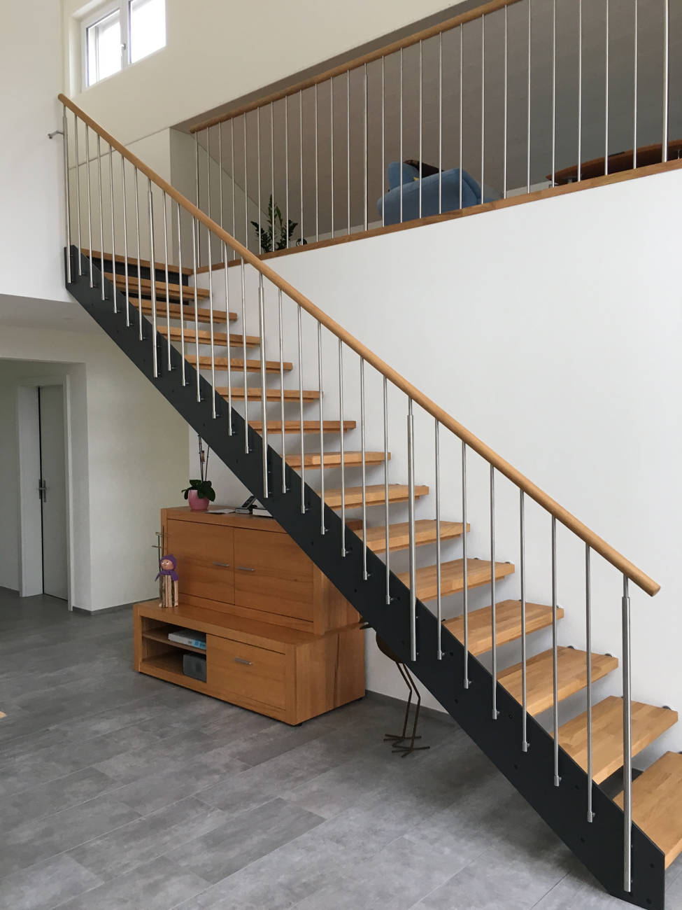 Loft-Treppe, Stufen in Eiche längsgezinkt geölt zwischen Vollkernplatte und Wand montiert. Geländer mit vertikalen Edelstahlsprossen und rundem Holzhandlauf. Kinderschutzleisten in Holz.