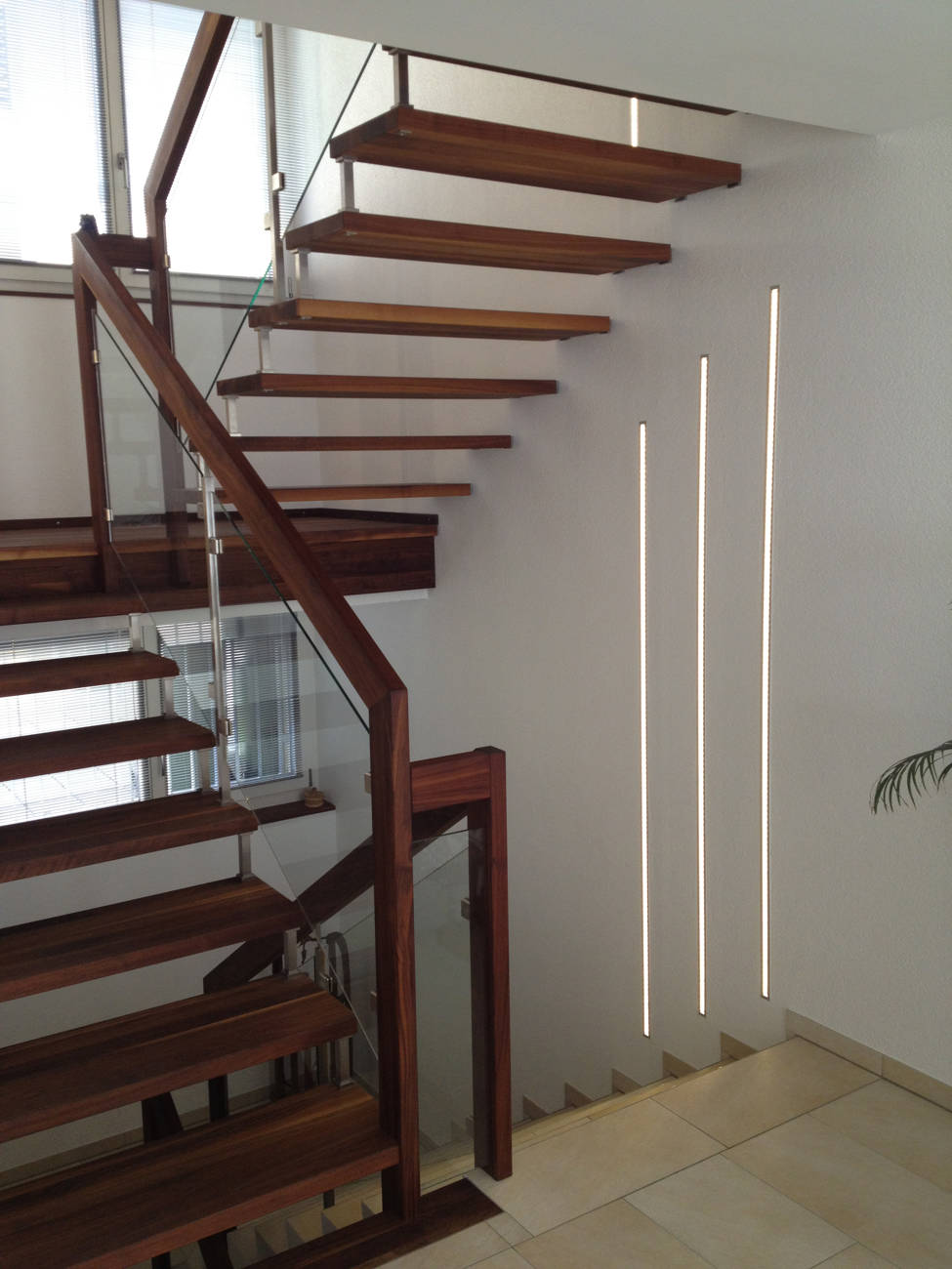 Podesttreppe in Amerikanischem Nussbaum, natur geölt. Geländer mit Edelstahlpfosten und Glasfüllungen.