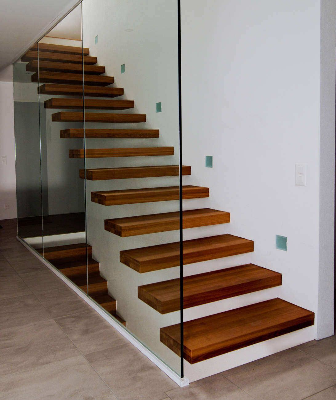 Marches à encorbelement en chêne couleur naturelle. Paroi en verre sur la hauteur totale de la pièce posé sur structure métallique.