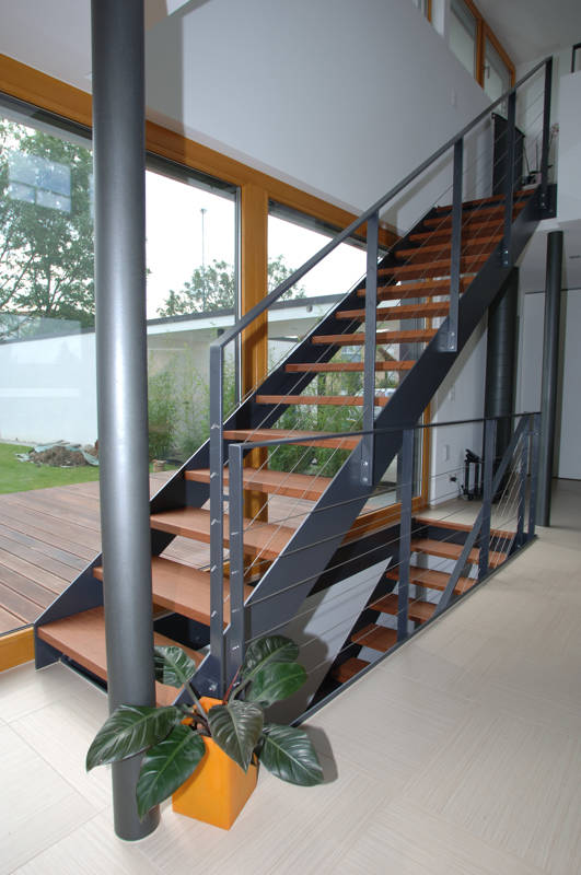 Escalier à limons métal avec marches en bois massif et une rampe composée d'une main courante et poteaux en fer plat avec remplissage câbles Ø 4 mm.