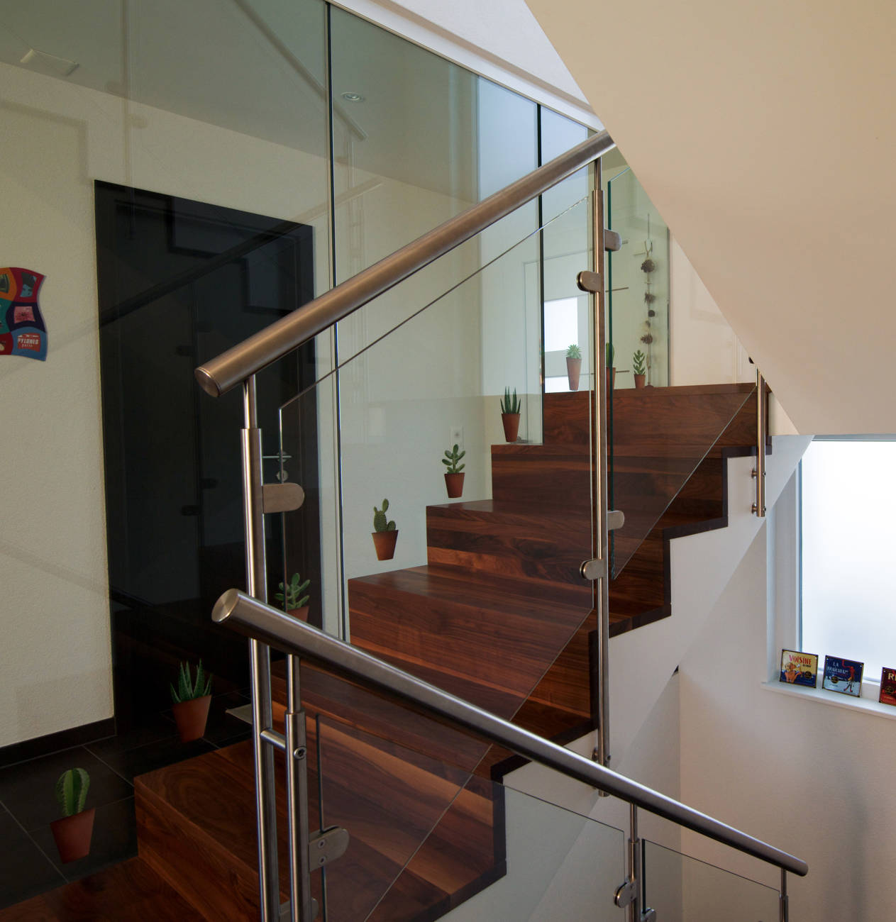 Stufen und Futterbretter in amerikanischem Nussbaum auf Betontreppe. Edelstahlpfosten, CNS-Handlauf und Verbundsicherheitsglas.