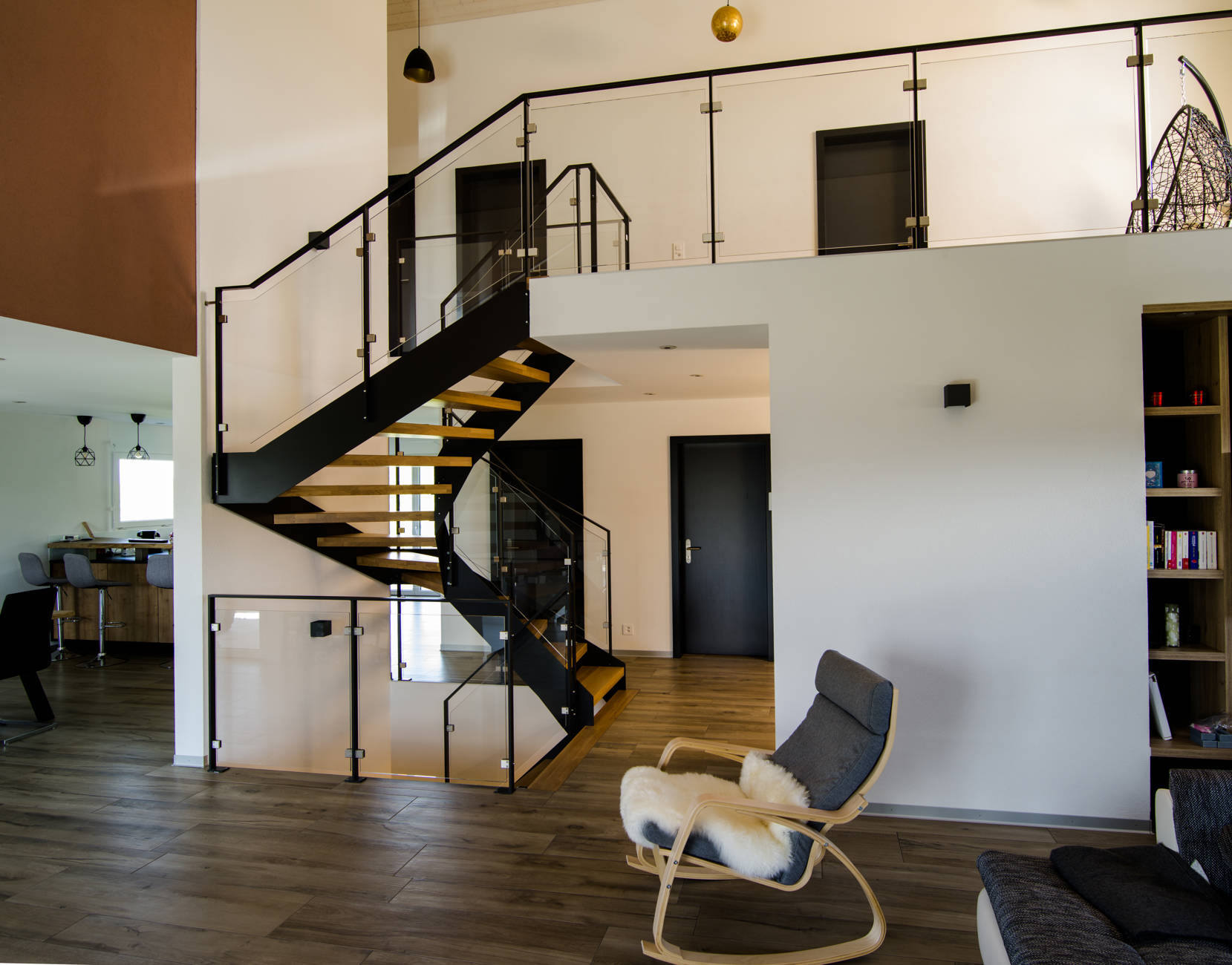 Metallwangentreppe mit Stufen in Eiche. Geländer aus Flachstahlrahmen mit Glasfüllung.