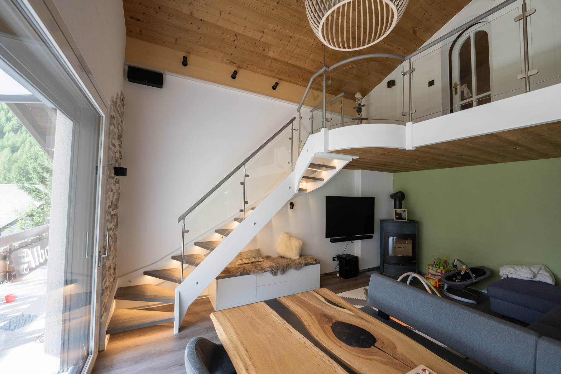 Holzwangentreppe mit Stufen in Eiche und Wangen weiss lackiert. Das Geländer ist eine Kombination aus Edelstahlpfosten, Holzhandlauf und Glasfüllung.